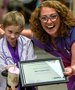 A young girl next to a doctor in scrubs holding a certificate