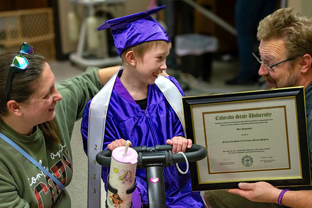 A young girl in a graduation cap and gown receives a diploma