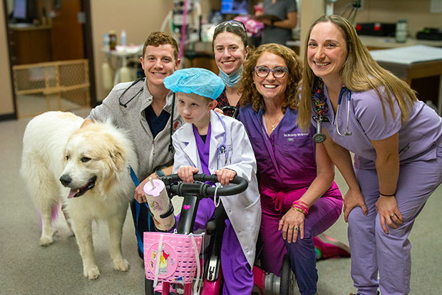 Group photo of a young girl, dog, and a veterinary team