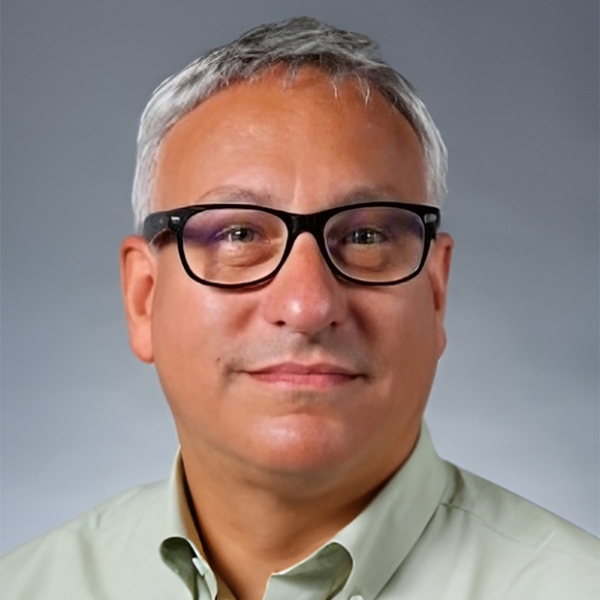 Man with short grey hair and glasses wearing a light green collared shirt